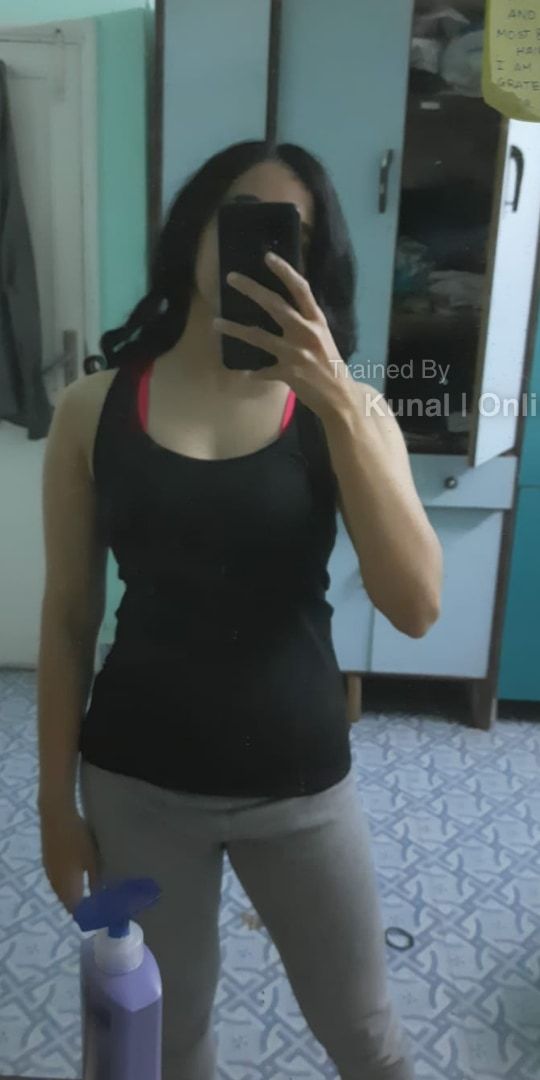 Mrunmayee before: a mirror selfie in a black vest and grey leggings, face covered by the phone.
